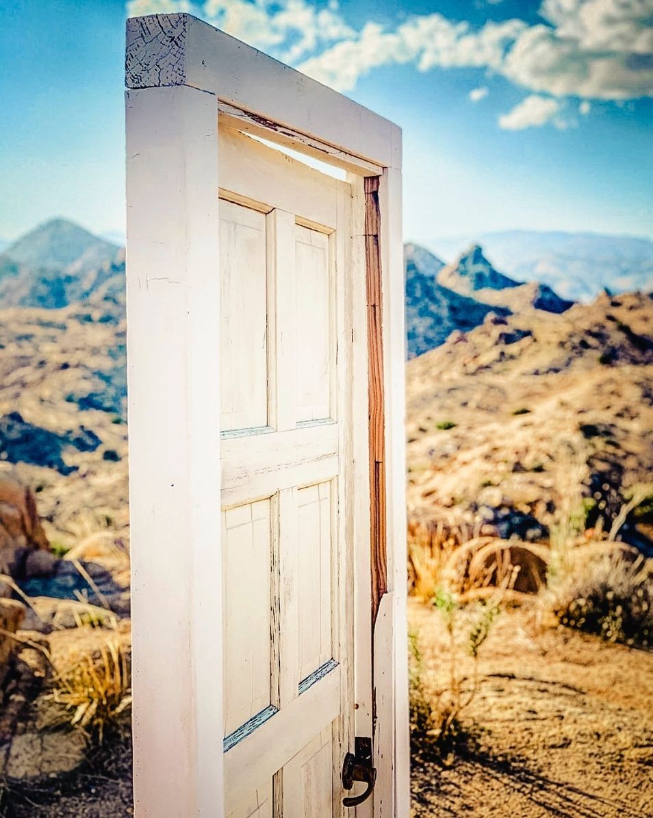 The free-standing white door installation at ESCAPE, framed against the high desert ridge