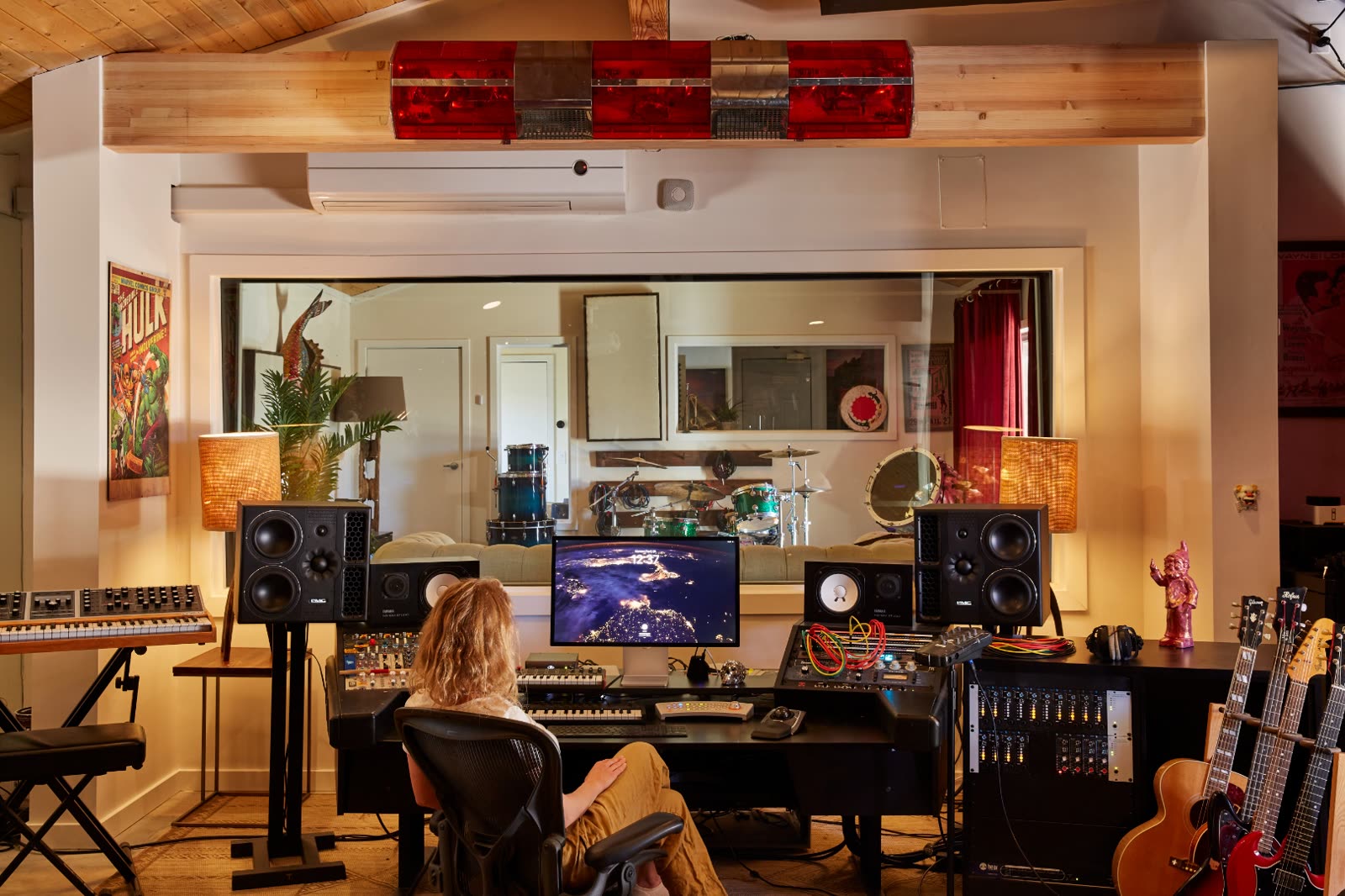 Studio One at ESCAPE — control room with Hulk poster, red light bar, modular synths, drum kit through the window