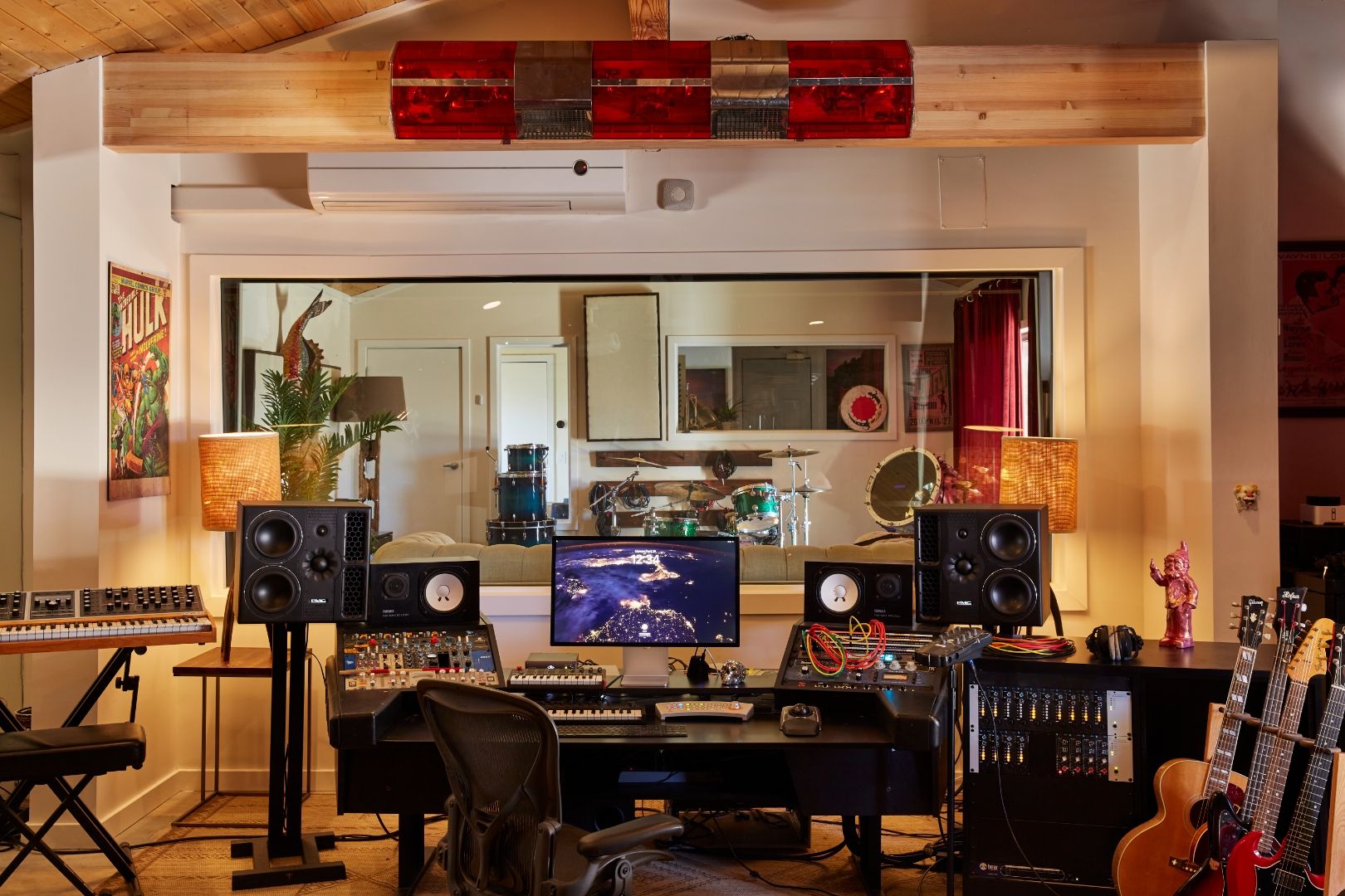 Studio One at ESCAPE — control room with Hulk poster, red light bar, modular synths, Aeron chair at the desk, drum kit through the window